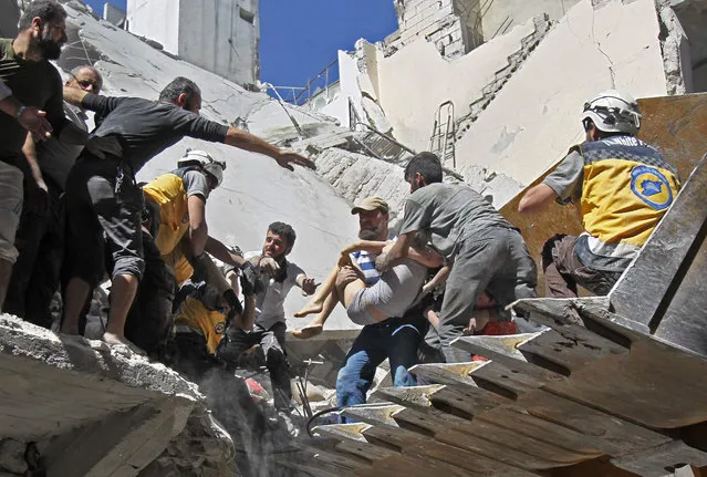 White Helmet rescue volunteers and civilians rescue a child from the rubble of a building destroyed during an air strike by Syrian regime forces and their allies on the town of Ariha, in the southern outskirts of SYria's Idlib province on May 27, 2019. (Photo by Amer Alhamwe/AFP Photo)