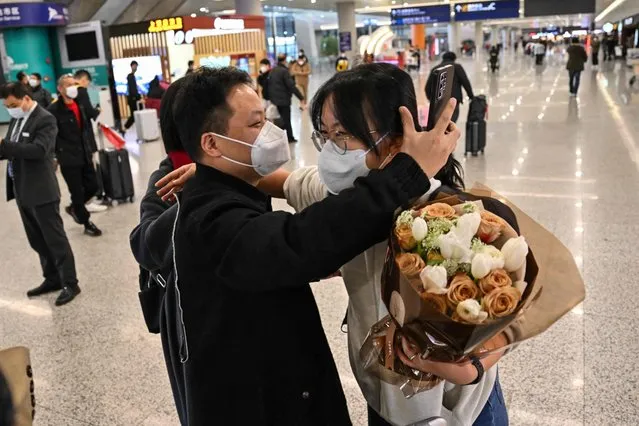 A passenger (R) receives a hug while leaving the arrival area of international flights at the Shanghai Pudong International Airport, in Shanghai on January 8, 2023. China lifted quarantine requirements for inbound travellers on January 8, ending almost three years of self-imposed isolation even as the country battles a surge in Covid cases. (Photo by Hector Retamal/AFP Photo)