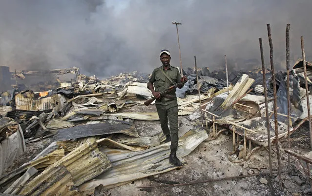 A Somali soldier walks through the wreckage after a fire engulfed the Somali capital's main market in Mogadishu, Monday, February 27, 2017. A police officer said the overnight inferno was moved by winds which started at the gold bazaar and rapidly spread into different areas of the market, razing large buildings, shops and food stores. (Photo by Farah Abdi Warsameh/AP Photo)