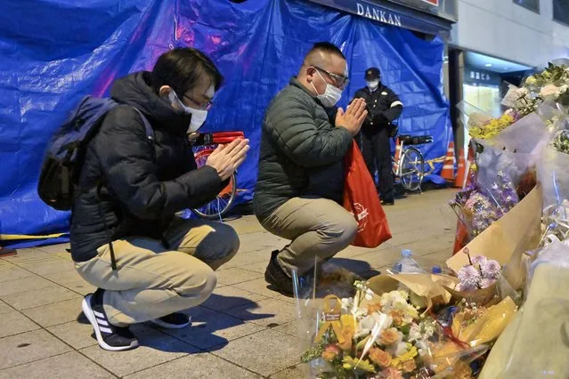 Mourners pray in front of offerings near a building, background, where a fire broke out, in Osaka, western Japan Thursday, December 30, 2021. The suspect in the fire that killed 25 people died Thursday at a hospital where he was being treated for burns and smoke inhalation, police said Friday. (Photo by Kyodo News via AP Photo)