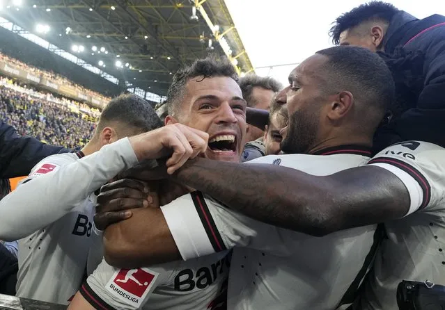 Leverkusen's Granit Xhaka, left, is embraced by Jonathan Tah as the team celebrates after Josip Stanisic scored in the last minute during the German Bundesliga soccer match between Borussia Dortmund and Bayer Leverkusen in Dortmund, Germany, Sunday, April 21, 2024. The match ended 1-1, Leverkusen is unbeaten since a record of 45 matches. (Photo by Martin Meissner/AP Photo)