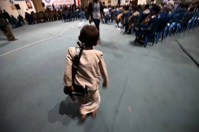 A boy holds a rifle while attending with his brother celebrations marking the 25th anniversary of Yemen's unification in Sanaa May 23, 2015. North and South Yemen were formally united in 1990. (Photo by Mohamed al-Sayaghi/Reuters)