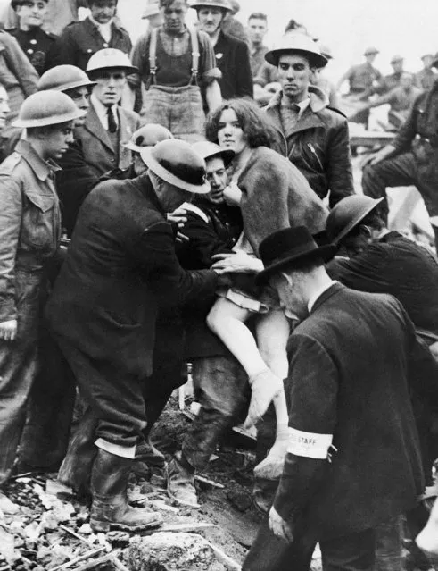 After working several hours through the wreckage of a bombed London, member of an Air Raid Protection lift Miss Betty Warboy clear of debris, October 31, 1940. She was the first of seven persons rescued from the shelter. (Photo by AP Photo)