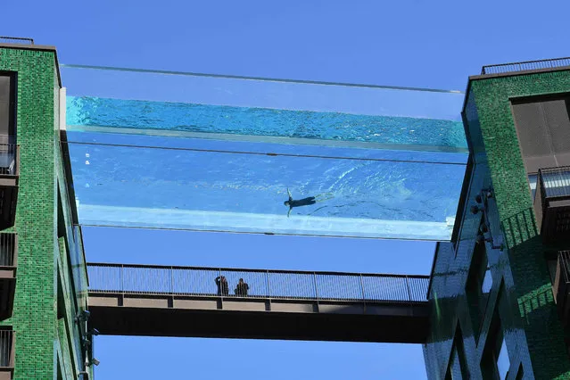 A model swims in a transparent acrylic swimming pool bridge that is fixed between two apartment blocks at Embassy Gardens next to the new US Embassy in south-west London on April 22, 2021. A world first, the transparent 25-metre-long outdoor pool, known as the Sky Pool, will allow residents to swim from one building to the other, 10 storeys above the ground. (Photo by Justin Tallis/AFP Photo)
