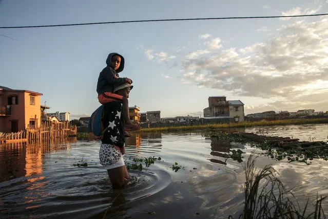 Residents walk in a flooded area of the 67-hectare Ankasina neighbourhood in Antananarivo on Januray 28, 2022 as Madagascar suffered flooding caused by a severe storm. Torrential rains from deadly Tropical Storm Ana subsided on Friday leaving tens of thousands of people across three countries in southern Africa cut off by flood damage, without power and living in shelters. The death toll stood at 86 across Madagascar, Mozambique and Malawi, as rescue crews battled on to access regions where roads and bridges had washed away. (Photo by Rijasolo/AFP Photo)