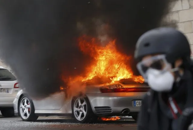A photographer runs away from a torched sports car during a demonstration against the French labour law proposal in Nantes, France, as part of a nationwide labor reform protests and strikes, April 28, 2016. (Photo by Stephane Mahe/Reuters)