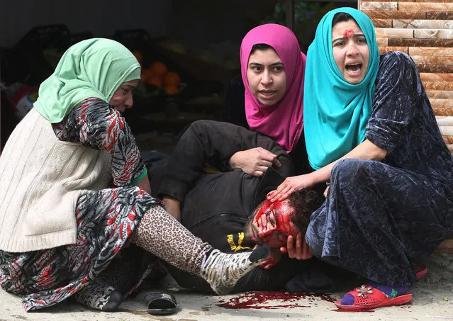 Iraqi women cry over their brother's body, who was killed by a mortar shell fired by Islamic State (IS) group jihadists on civilians who were gathered to receive aid, in Al-Risala neighbourhood on March 22, 2017, as an ongoing offensive by Iraqi forces to retake the city from the group continues. Iraqi forces launched a major operation to recapture west Mosul – the most-populated urban area still held by IS – on February 19, and have retaken a series of neighbourhoods from the jihadists. (Photo by Ahmad Al-Rubaye/AFP Photo)