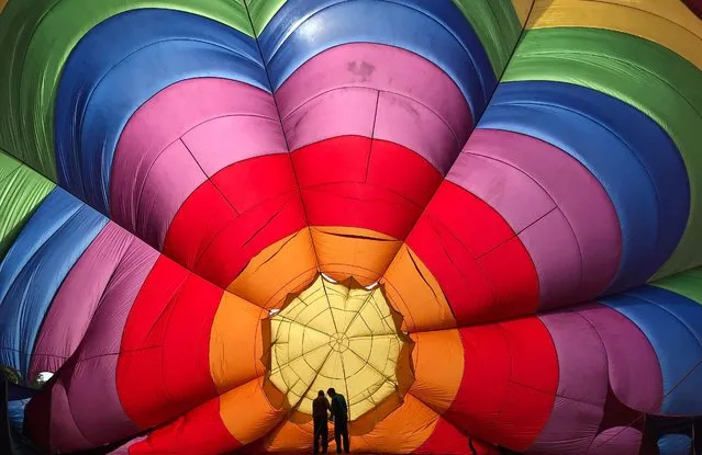 Two crew members inspect a partially inflated balloon at the annual Bristol hot air balloon festival in Bristol, Britain, August 8, 2019. (Photo by Toby Melville/Reuters)