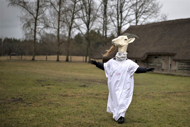 A performer wearing a traditional carnival mask takes part in Shrovetide celebrations, in Rumsiskes village, some 89 kilometers (56 miles) north of Vilnius, Lithuania, Saturday, February 18, 2023. A strange scenario took place in this central Lithuania village this weekend as chanting devils, goats, witches and others filled the streets to chase winter away. Shrovetide is a traditional Lithuanian holiday marking the end of winter. (Photo by Mindaugas Kulbis/AP Photo)