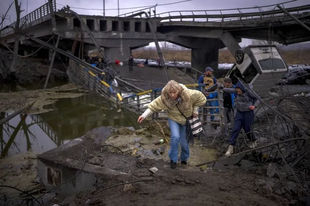 A woman runs as she flees with her family across a destroyed bridge in the outskirts of Kyiv, Ukraine, Wednesday, March 2. 2022. Russia renewed its assault Wednesday on Ukraine’s second-largest city in a pounding that lit up the skyline with balls of fire over populated areas, even as both sides said they were ready to resume talks aimed at stopping the new devastating war in Europe. (Photo by Emilio Morenatti/AP Photo)