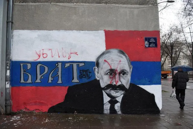 A man walks next to a mural of Russian President Vladimir Putin, which has been vandalized with red spray paint and the word “Murderer” written above the original text reading: “Brother”, following Russia's invasion of Ukraine, in Belgrade, Serbia on March 6, 2022. (Photo by Zorana Jevtic/Reuters)
