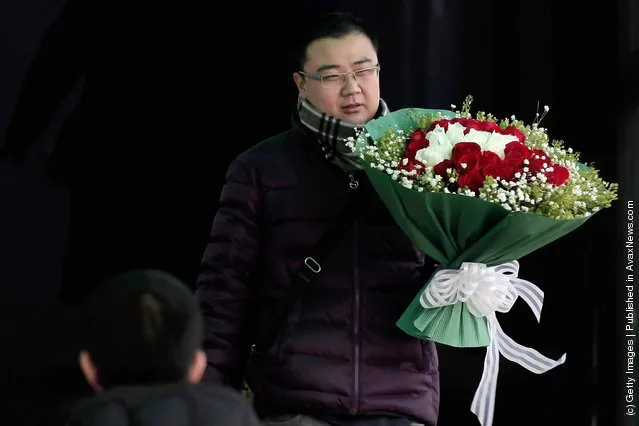 A customer holding a bouquet of roses walks out of the flower shop on Valentine's Day