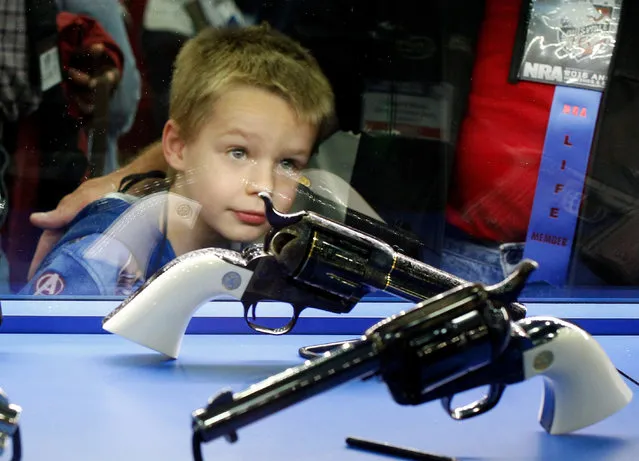 Asher Thomson (5) looks over a pair of Colt revolvers at the National Rifle Association's annual meetings and exhibits show in Louisville, Kentucky, May 21, 2016. (Photo by John Sommers II/Reuters)