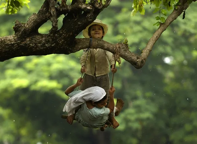 Two kids play on a swing, in Usulutan, 110 km south of San Salvador on July 08, 2015. Government authorities estimate that more than 40,000 farmers – mostly maize growers – have been affected by the drought. (Photo by Marvin Recinos/AFP Photo)
