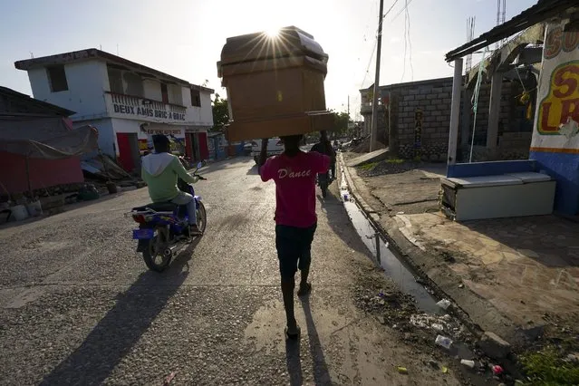 A worker carries a coffin form a storage depot to a funeral home in Les Cayes, Haiti, Wednesday, August 18, 2021. A 7.2-magnitude earthquake struck the southwestern part of the hemisphere's poorest nation on Aug. 14. (Photo by Fernando Llano/AP Photo)