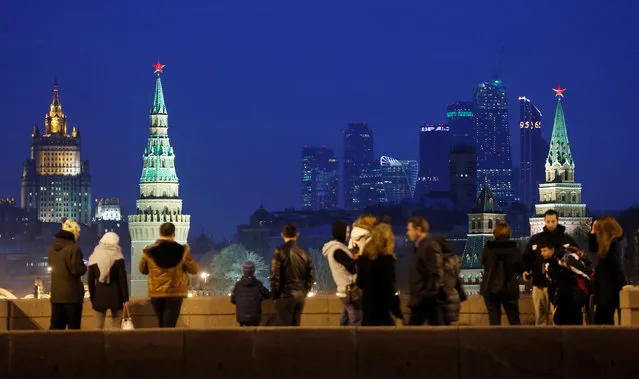People stand on the Great Moskvoretsky Bridge, with the headquarters of Russian Foreign Ministry, the Kremlin towers and the Moscow International Business Center also known as “Moskva-City”, seen in the background, in central Moscow, Russia, March 28, 2016. (Photo by Maxim Shemetov/Reuters)