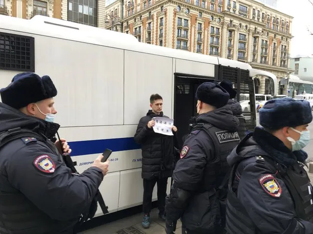 Dmitry Reznikov holding a blank piece of paper with eight asterisks that could have been interpreted as standing for “No to war” in Russian, stands next to a Police van as he was detained in Moscow, Russia, Sunday, March 13, 2022. The court found him guilty of discrediting the armed forces and fined him 50,000 rubles ($618) for holding the sign in central Moscow in a mid-March demonstration that lasted only seconds before police detained him. (Photo by SOTA via AP Photo)