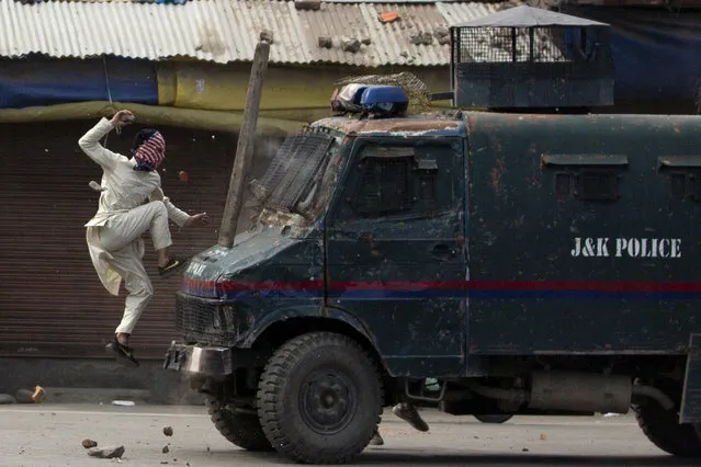 A masked Kashmiri protester jumps on the bonnet of an armored vehicle of Indian police as he throw stones at it during a protest in Srinagar, Indian controlled Kashmir, Friday, May 31, 2019. Government forces in Indian controlled Kashmir fired tear gas and pellets to disperse hundreds of protesters who clashed with them during a protest against the recent killing of Kashmir rebel leader and also an annual protest marking Al-Quds Day. The last Friday of the Islamic holy month of Ramadan is observed in many Muslim communities as Al-Quds Day, or Jerusalem Day, as a way of expressing support to the Palestinians and emphasizing the importance of Jerusalem to Muslims. (Photo by Dar Yasin/AP Photo)