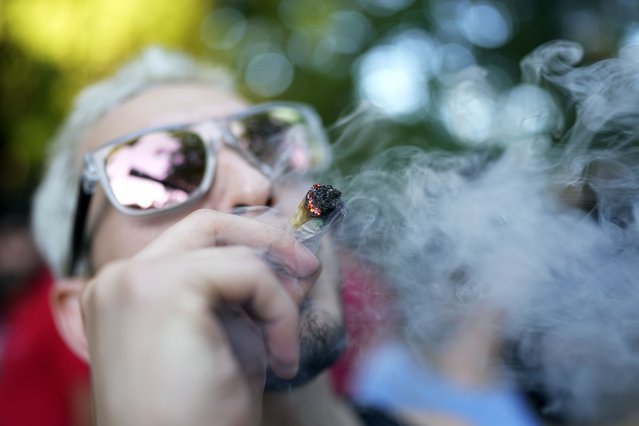 A youth smokes marijuana during the Open Plaza festival organized by the Granjamadre marijuana farm, in Asuncion, Paraguay, Sunday, June 4, 2023. (Photo by Jorge Saenz/AP Photo)