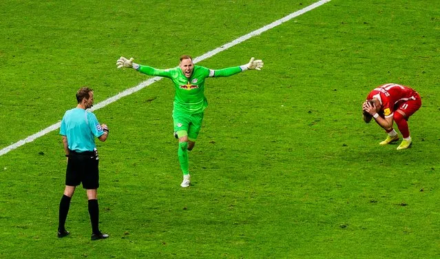 Referee Sascha Stegemann (L) looks on as Leipzig's Hungarian goalkeeper Peter Gulacsi (C) celebrates after Freiburg's Bosnian forward Ermedin Demirovic (R) missed his penalty kick during the German Cup (DFB Pokal) final football match between SC Freiburg and RB Leipzig at the Olympic Stadium in Berlin on May 21, 2022. (Photo by John MacDougall/AFP Photo)