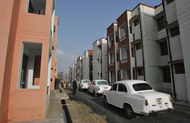 Bullet-proof Ambassador cars, manufactured by Hindustan Motors, which are used by the government officials, are parked beside newly constructed flats built for Kashmiri Hindu or Pandit migrants during the inauguration ceremony of the Jagti Township on the outskirts of Jammu March 4, 2011. (Photo by Mukesh Gupta/Reuters)