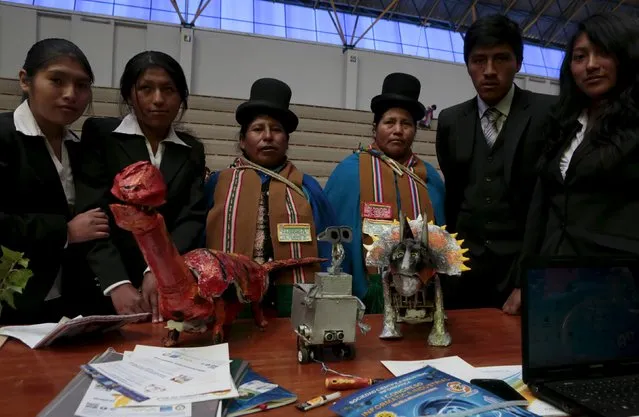 Students (L) pose with their relatives as they present dinosaur robots built with recycled materials during the annual robotics fair supported by the Bolivian Education Ministry in La Paz, August 10, 2015. (Photo by David Mercado/Reuters)