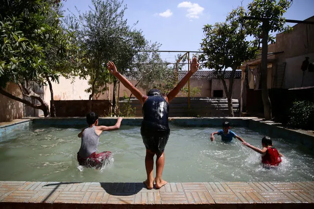 Boys swim to cool down from heat inside a swimming pool, in the rebel held besieged town of Douma, eastern Damascus suburb of Ghouta, Syria, June 23, 2016. (Photo by Bassam Khabieh/Reuters)