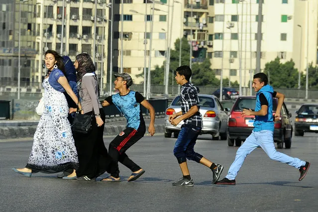 In this August 20, 2012 file photo, an Egyptian youth, trailed by his friends, gropes a woman crossing the street with her friends in Cairo, Egypt. Hundreds of Egyptian women and girls have come out to denounce sexual harassment and share personal stories about it on social media, breaking a taboo and raising the ire of the country’s conservative majority. In posts on Facebook and Twitter from the weekend to Wednesday, rare, candid stories focused on women’s first experiences of harassment, almost all of which occurred in childhood and some involving family members and teachers. (Photo by Ahmed Abd El Latif/AP Photo/El Shorouk Newspaper)