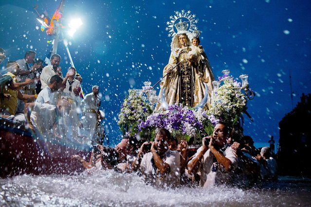 Carriers of the Great God Power brotherhood unload Virgen del Carmen statue after its journey on July 15, 2014 at Puerto de la Cruz dock on the Canary island of Tenerife, Spain. Since 1921, the statue of the Virgen del Carmen, patron saint of fishermen, has been carried with great fanfare annually as part of July Festivities to the Puerto de la Cruz dock where, at the end of its procession, it is hoisted aboard a decorated boat. (Photo by Gonzalo Arroyo Moreno/Getty Images)