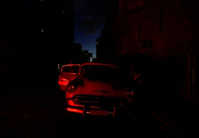 A man cleans his vintage car during a blackout as the country's electrical grid collapsed again on Sunday, according to Cuba's energy and mines ministry, in the latest setback to the government's efforts to restore power to the island, in Havana, Cuba on October 20, 2024. (Photo by Norlys Perez/Reuters)