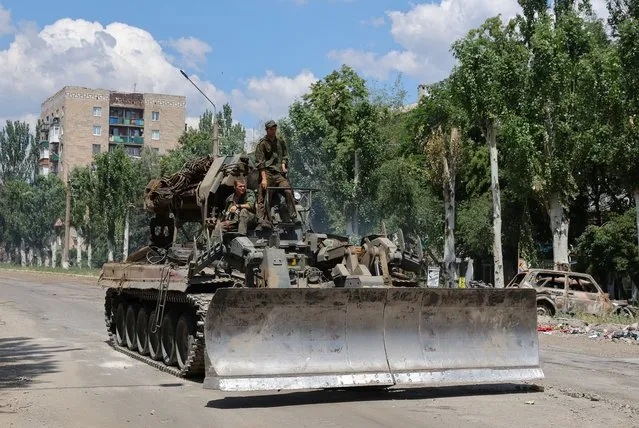 Service members of pro-Russian troops ride on top of a combat engineering vehicle during Ukraine-Russia conflict in the city of Lysychansk in the Luhansk Region, Ukraine on July 4, 2022. (Photo by Alexander Ermochenko/Reuters)