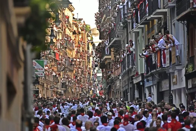 People run through the streets ahead of fighting bulls and steers during the first day of the running of the bulls at the San Fermin Festival in Pamplona, northern Spain, Thursday, July 7, 2022. Revelers from around the world flock to Pamplona every year for nine days of uninterrupted partying in Pamplona's famed running of the bulls festival which was suspended for the past two years because of the coronavirus pandemic. (Photo by Alvaro Barrientos/AP Photo)