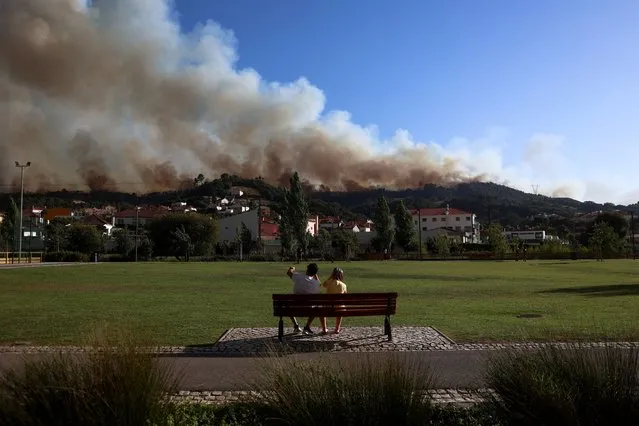 People watch as smoke rises from a wildfire in Venda do Pinheiro, Mafra, Portugal, July 31, 2022. (Photo by Pedro Nunes/Reuters)
