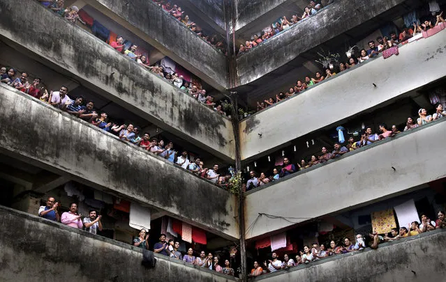 People clap from balconies in show of appreciation to health care workers at a Chawl in Mumbai, India, Sunday, March 22, 2020. India is Sunday observing a 14-hour “people's curfew” called by Prime Minister Narendra Modi in order to stem the rising coronavirus caseload in the country of 1.3 billion. (Photo by Rafiq Maqbool/AP Photo)