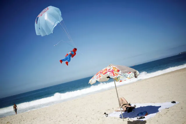 A toy tied to a small parachute is seen next to a sunbathing woman on Copacabana beach in Rio de Janeiro, Brazil, May 2, 2016. (Photo by Nacho Doce/Reuters)