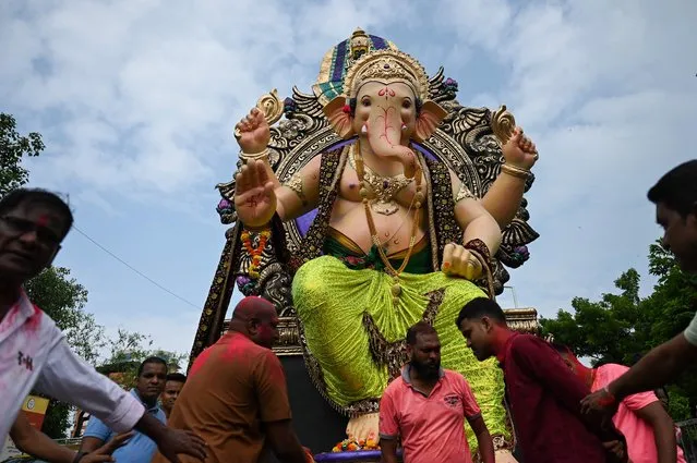 Devotees carry an idol of elephant-headed Hindu deity Ganesha during a procession ahead of the Ganesh Chaturthi festival in Mumbai on August 30, 2022. (Photo by Punit Paranjpe/AFP Photo)