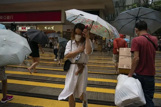 People holding umbrellas under strong wind walk pass a crosswalk as tropical storm Ma-on passes Hong Kong, Thursday, August 25, 2022. Tropical Storm Ma-on made landfall in southern China’s Guangdong province on Thursday after bringing rain and stiff winds to Hong Kong, where the stock market was closed for the morning session due to the storm. (Photo by Anthony Kwan/AP Photo)