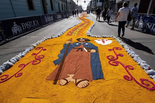 Parishioners walk in a street decorated with colored carpets made of flowers, colored sawdust and recycled plastic, for the procession of the Virgen de Los Angeles, in Cartago, Costa Rica, on September 04, 2022. During the procession, the image of the Virgen de Los Angeles  – Costa Rica's patron saint, which spent a month in the Cathedral of Our Lady of Mount Carmel – is carried to the Basilica of Los Angeles. (Photo by Ezequiel Becerra/AFP Photo)