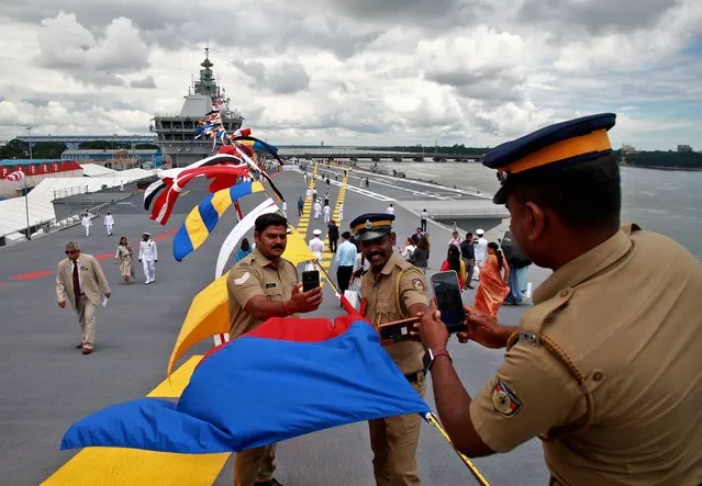 Police officers take use their mobile phones to take photographs on the flight deck of India's first home-built aircraft carrier INS Vikrant after its commissioning ceremony at a state-run shipyard in Kochi, India, September 2, 2022. (Photo by Sivaram V/Reuters)