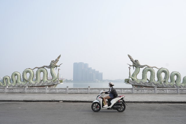 A woman wearing a face mask rides under a hazy sky in Hanoi, Vietnam, Thursday November 14, 2024. (Photo by Hau Dinh/AP Photo)