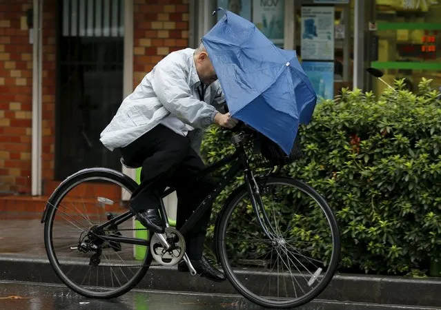 A man holding onto an umbrella as he cycles in heavy rain caused by typhoon Etau in Tokyo's business district September 9, 2015. (Photo by Toru Hanai/Reuters)