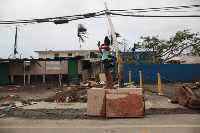 A woman stands on an overturned refrigerator while trying to get a mobile phone signal, after Hurricane Maria hit the island in September, in Toa Baja, Puerto Rico on October 19, 2017. (Photo by Alvin Baez/Reuters)