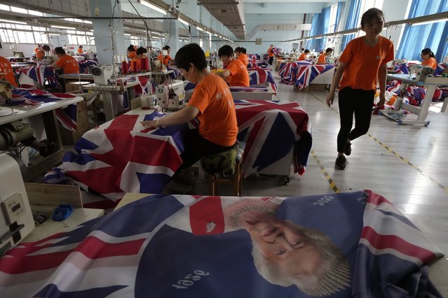 Workers produce British flags at the Shaoxing Chuangdong Tour Articles Co factory in Shaoxing, in eastern China's Zhejiang province, Friday, September 16, 2022. Ninety minutes after Queen Elizabeth II died, orders for thousands of British flags started to flood into the factory south of Shanghai. (Photo by Ng Han Guan/AP Photo)