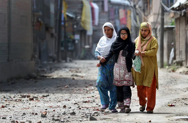 Two women and a girl make their way along a street littered with rocks thrown by protestors in Srinagar as the city remains under curfew following weeks of violence in Kashmir August 19, 2016. (Photo by Cathal McNaughton/Reuters)