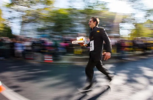 A waiter takes part in the Berliner Kellnerlauf (Berlin Waiter Run) in Berlin October 5, 2014. The competition was founded in Berlin years after the World War Two. (Photo by Hannibal Hanschke/Reuters)