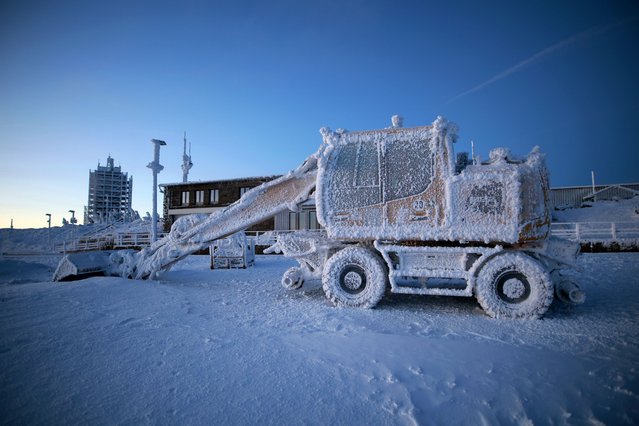 View of an icy excavator at the Brocken station in Saxony-Anhalt, Germany on January 8, 2024. In the early morning light, the Brocken is visible again after days without fog. Icy polar cold brings temperatures of minus 16 degrees Celsius to the Brocken summit. Frost and fog have left a bizarre icy landscape on the Harz summit. (Photo by Matthias Bein/dpa)