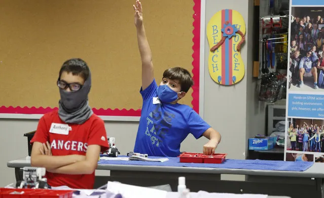 Amid concerns of the spread of COVID-19, Aiden Trabucco, right, wears a mask as he raises his hand to answer a question behind Anthony Gonzales during a summer STEM camp at Wylie High School Tuesday, July 14, 2020, in Wylie, Texas. (Photo by L.M. Otero/AP Photo)