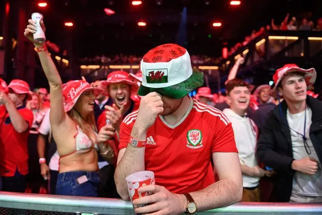 A lone Wales fan reacts as England fans celebrate their team's goal while watching the Qatar 2022 World Cup Group B football match between Wales and England at the BUDX FIFA Fan Festival at Outernet in London on November 29, 2022. (Photo by Justin Tallis/AFP Photo)