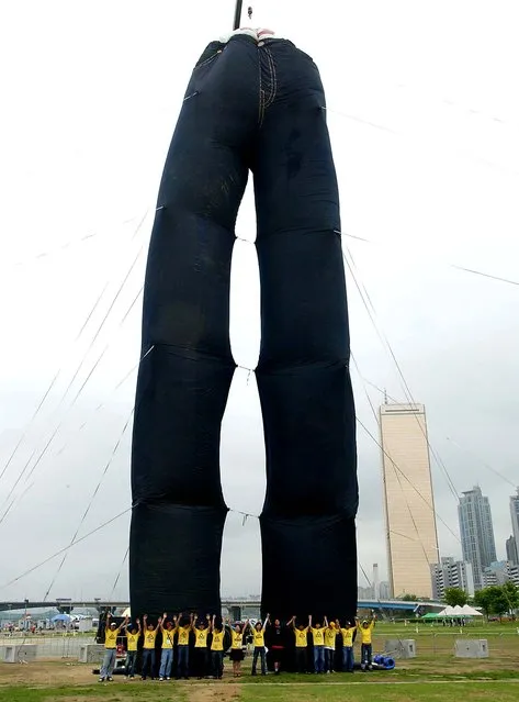 People in Seoul, South Korea, pose in front of the Levis Big Jeans, which at 30m high are recognized as the world's largest pair of blue jeans, May 1, 2005. (Photo by Chung Sung-Jun)