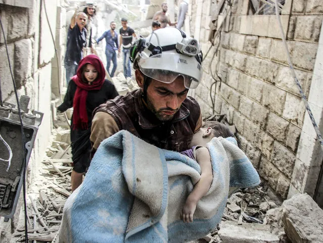 A search and rescue member holds a baby wrapped with a blanket after Assad Regime's forces carried out air strikes over the de-conflict zone, at the Jisr al-Shughur district of Idlib, Syria on September 25, 2017. (Photo by Hadi Kharat/Anadolu Agency/Getty Images)